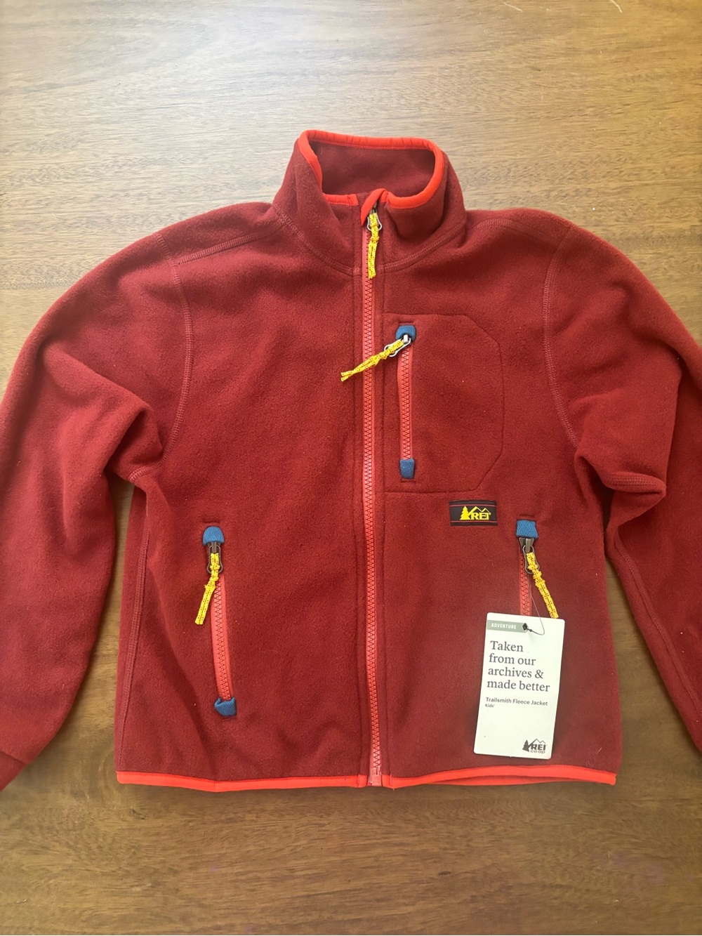 REI Kids Red Fleece Jacket with Yellow Zipper Pulls and Blue Accents